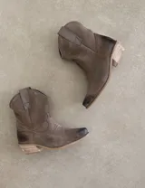 Botas cortas negras de cuero con bordados blancos estilo cowboy.