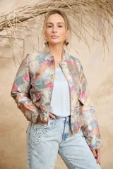 Bomber estampada con motivos florales y de aves en tonos pastel, con cuello mao, cierre frontal con botones dorados, bolsillos laterales con solapa y puños elásticos.
