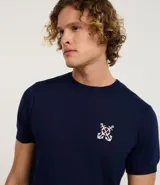 Remera azul marino de viscosa con cuello redondo y mangas cortas. Presenta un bordado con motivos marineros en el frente. Corte regular.