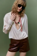 Camisa color borgoña de satén con cuello solapa, escote en pico, manga larga y cierre frontal con botones.