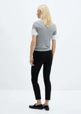 Pantalón negro de diseño crop, corte skinny y tiro medio. Cuenta con trabillas, dos bolsillos laterales, dos bolsillos de ribete en la parte posterior, cierre de cremallera y botón, y forro interior.