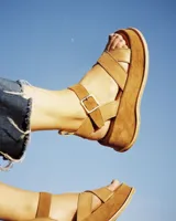 Sandalias negras de cuero vacuno con textura reptil, plataforma y hebilla plateada.