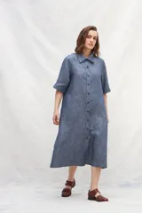 Vestido camisero midi color beige, de lino, con abotonadura frontal completa, manga ranglan, bolsillos laterales y un volante en el ruedo.