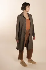 Camisa larga color crema con rayas verticales finas en gris, con botones dorados y bolsillo plaque en la delantera.