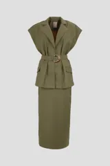 Conjunto color verde militar compuesto por un blazer sin mangas con cuello solapa, cierre cruzado con botón y cinturón con hebilla dorada, y una falda midi de corte recto.