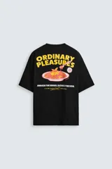 Camiseta negra de corte relajado, cuello redondo y manga corta. Presenta estampado frontal con la frase "Comfort Food!!! Our Daily Specials" y un dibujo de una flor.