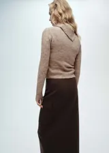 Sweater color beige de tejido de punto, con cuello solapa alto y mangas largas.
