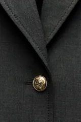 Blazer recta confeccionada en hilatura con viscosa, color gris oscuro. Tiene cuello solapa de muescas, manga larga con abertura y botones, bolsillos de plastrón en delantero, forro interior a tono y cierre frontal con botones.