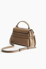 Cartera bandolera color visón, con correa ajustable y asa de mano. Presenta solapa con cierre magnético y trabilla decorativa con hebilla metálica.