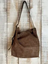 Bolso marrón de cuero con textura, tipo hobo, con correa larga regulable y hebilla dorada.