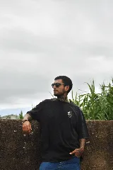 Remera negra de manga corta con cuello redondo y estampado pequeño de un jarrón con flores en el pecho.