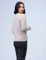 Buzo de tejido melange color beige con puntos oscuros, cuello redondo y manga larga.