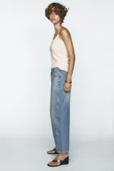 Pantalón de jean celeste de corte amplio, con tiro medio, cinco bolsillos y costuras torcidas.