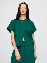 Camisa de muselina color blanco hueso, con cuello mao, manga corta y cierre frontal con botones.