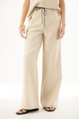 Pantalón de lino color beige, de corte palazzo, con cintura alta y lazo de ajuste.