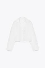 Camisa corta blanca con bordados perforados, cuello solapa, escote pico y manga larga abullonada.