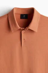 Remera polo color ladrillo de punto de algodón liviano, corte slim fit, manga corta, cuello clásico con tapeta de botones y bajo recto.