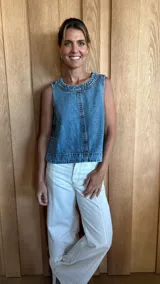 Chaleco de jean celeste con cuello redondo y diseño sin mangas. Presenta costuras verticales en el frente y ruedo desflecado.