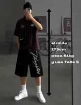 Bermuda negra de gabardina pesada con costuras rojas y estampado lateral blanco con el texto "Plagstar".