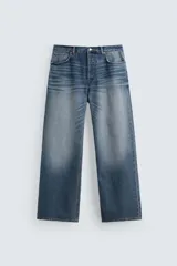 Pantalón de jean azul con efecto lavado, corte flare y baggy, tiro alto, cinco bolsillos y cierre frontal con botones.