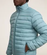 Campera puffer ultraligera color beige, con cuello alto, cierre por cremallera y bolsillos con cremallera. Incluye bolso de almacenamiento.