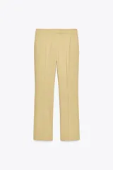 Pantalón color arena de tiro alto con bolsillos delanteros y corte acampanado. Cierre frontal con cremallera y gancho metálico.