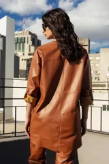 Chaqueta negra de cuero ovino con corte recto y lazo de ajuste en la cintura.