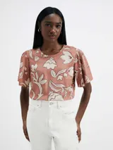 Blusa de manga corta con estampado floral en tonos rosados y blancos.