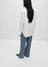 Camisa blanca de popelina de algodón y lyocell, con bordado floral en el frente, corte oversize, cuello camisero, mangas largas con puños abotonados y cierre frontal con botones.