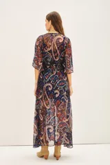 Vestido largo con estampado paisley en tonos azul, negro, rojo y dorado. Tiene escote en V, mangas cortas amplias, elástico en la cintura con lazo y está confeccionado en viscosa con jacquard de lurex.