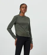 Blusa de viscosa color verde militar, de manga larga y cuello redondo. Presenta corte peplum con volado en el bajo y textura acanalada.