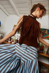 Gargantilla de cuero marrón con flecos y cierre con lazo. El collar de esferas marrones que se ve en la imagen es solo para estilismo.