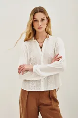 Camisa blanca de manga larga con cuello mao y escote en V, con bordados negros en el frente y puños.