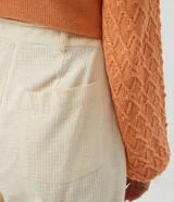 Pantalón zanahoria color crema con textura de cuadros, cordón ajustable en la cintura, bolsillos delanteros y traseros.