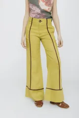 Pantalón acampanado color amarillo ocre con costuras marrones en contraste.