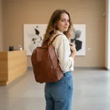 Mochila de eco cuero color marrón, con diseño estructurado y bolsillo frontal con cierre.