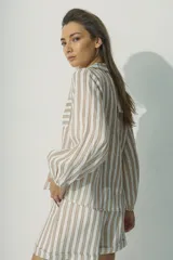 Camisa de manga larga con cuello camisero y cierre frontal con botones. Diseño a rayas verticales color beige y blanco, con dos bolsillos de parche en el pecho.