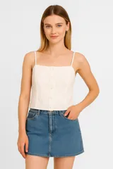 Top blanco de algodón con breteles finos, bordado con motivos florales, cuello cuadrado y cierre frontal con botones.