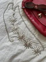 Cadena plateada para la cintura con dijes de soles sonrientes.