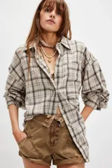 Camisa de franela de algodón con estampado a cuadros en tonos beige, blanco y marrón oscuro. Presenta un corte amplio y holgado, cuello camisero y botones frontales.