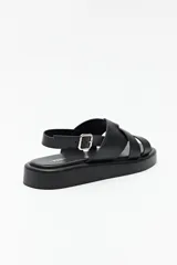 Sandalias negras de símil cuero con agarre ajustable en el talón y capellada entrelazada. Plataforma de 3 cm de alto.