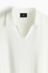 Remera blanca de punto texturizado con cuello y miniabertura en V.