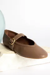 Ballerinas negras de cuero con tira sobre el empeine y hebilla dorada.