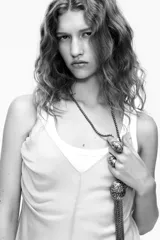 Collar largo con cadena dorada de eslabones metálicos. Colgante con medalla labrada en blanco y negro con flecos dorados. Cierre con mosquetón.