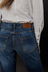 Jean azul gastado de corte recto (boot cut) levemente oxford desde la rodilla, con cintura media entallada y proceso de gastado localizado.