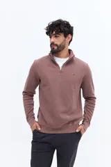 Buzo de algodón color verde musgo, con cuello alto y cierre frontal parcial. Presenta puños y cintura acanalados, y un pequeño logo bordado en el pecho.