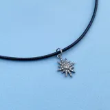 Collar con cordón negro símil cuero, cierre en plata 925 y dije de acero plateado en forma de estrella con circonitas.
