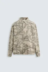Sobrecamisa color beige con estampado abstracto en tonos grises, de corte relaxed fit, cuello solapa, manga larga con puños abotonados, bolsillos de plastrón en el pecho, efecto lavado y cierre frontal con botones.