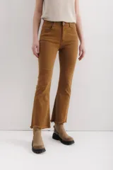 Pantalón jean marrón acampanado con detalle desflecado en el bajo y tiro medio.