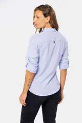 Camisa color beige de lino, de manga larga con botones metálicos personalizados y presilla en la manga. Tiene cuello clásico, cierre frontal parcial con botones y bolsillo de parche en el pecho.